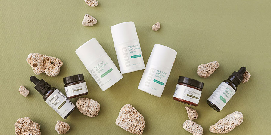 several different skincare products by the brand Nora and several stones with green background